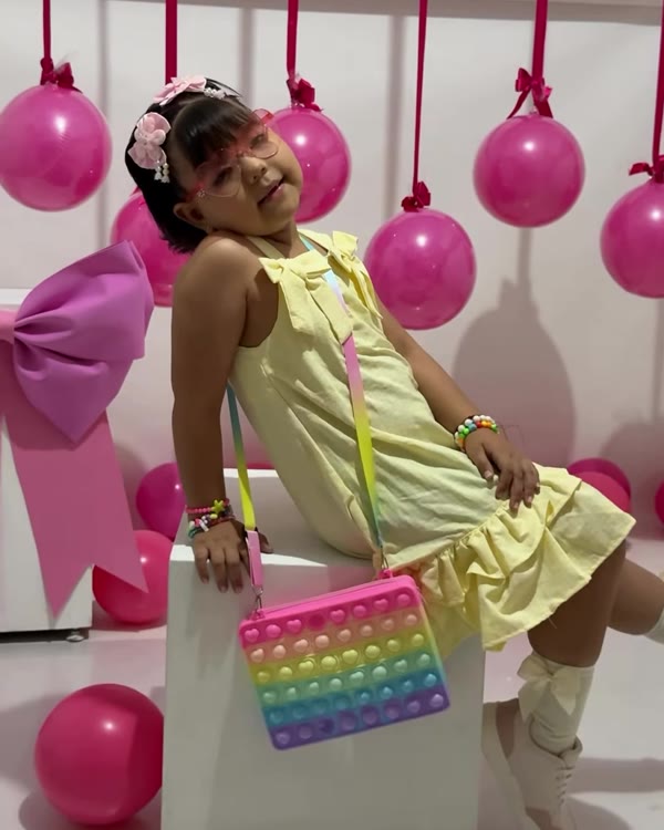 Luciana posa sentada durante su sesión de fotos, rodeada de globos rosados